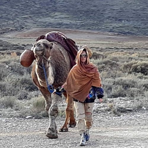 hombre con un poncho llevando un camello a pie